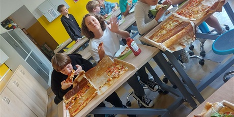 Powiększ grafikę: Wielobarwna fotografia w kształcie prostokąta przedstawiająca uczniów klasy 5F, którzy jedzą pizzę własnoręcznie przez siebie przygotowaną.