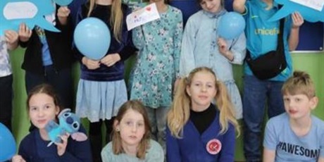Powiększ grafikę: Wielobarwna grafika w kształcie prostokąta stojącego, przedstawiająca dziewięcioro uczniów ubranych na niebiesko trzymających niebieskie balony i niebieskie chmurki z wypisanymi prawami dziecka. W tle przygotowana niebieska gazetka ilustrująca obchody Międzynarodowego Dnia Dziecka. 