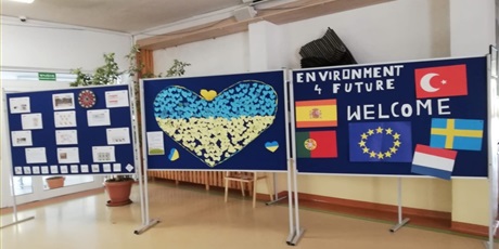 Powiększ grafikę: Barwna fotografia w kształcie prostokąta leżącego. W centralnej części zdjęcia znajduje się tablica powitalna na korytarzu szkolnym – napis Welcome i flagi krajów – biorących udział w projekcie Environment 4 Future.