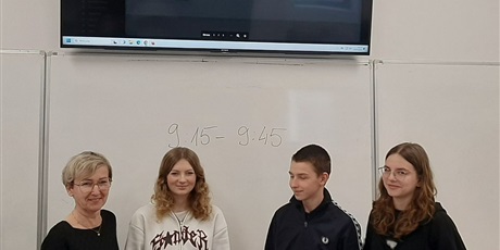 Powiększ grafikę: Barwna fotografia w kształcie prostokata leżącego przedstawiająca troje uczniów klasy 8 wraz z nauczycielką w sali szkolnej.