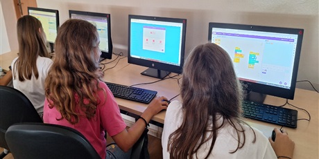 Powiększ grafikę: Wielobarwna fotografia w kształcie prostokąta leżącego przedstawiająca uczniów sieczących w sali komputerowej podczas pracy na komputerach.