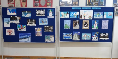 Powiększ grafikę: Zdjęcie w kształcie leżącego prostokąta przedstawiające dwie tablice. Na tablicach znajduje się napis V Międzyszkolny Konkurs Plastyczny "Zimowy Pejzaż" oraz prace plastyczne wykonane przez uczniów prezentujące zimowe krajobrazy. 