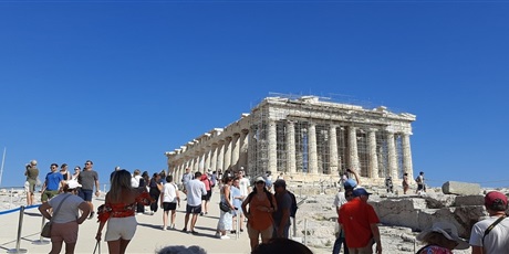 Powiększ grafikę: Barwna fotografia w kształcie prostokąta leżącego, przedstawiająca grupę osób – uczestników projektu oraz innych zwiedzający idących w kierunku Partenonu – świątyni poświęconej Atenie Partenos.