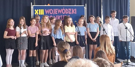 Powiększ grafikę: Barwna fotografia w kształcie prostokąta leżącego przedstawiająca kilkunastoosobową grupę nastolatków na scenie.