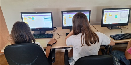 Powiększ grafikę: Wielobarwna fotografia w kształcie prostokąta leżącego przedstawiająca uczniów sieczących w sali komputerowej podczas pracy na komputerach.